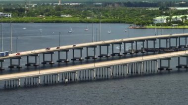 Aerial view of Barron Collier Bridge and Gilchrist Bridge in Florida with moving traffic. Transportation infrastructure in Charlotte County connecting Punta Gorda and Port Charlotte over Peace River.