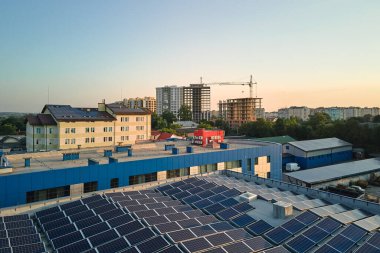 Sanayi binasının çatısına yeşil ekolojik elektrik üretmek için monte edilen mavi fotovoltaik güneş panellerinin hava görüntüsü. Sürdürülebilir enerji konsepti üretimi.