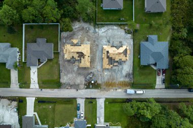 Florida 'nın banliyö bölgesinde inşaat halindeki ahşap çatı iskeleti yapısı olan bitmemiş bir ev üzerinde çalışan inşaatçıların hava görüntüsü..