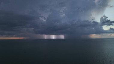 Şiddetli yağış mevsiminde gün batımında okyanus yüzeyinde kara uğursuz fırtına bulutları bulutları oluşuyor..