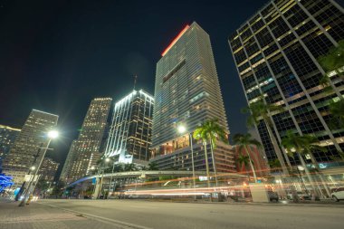 Florida 'da Miami Brickell' in şehir merkezinin gece manzarası. Modern Amerikan megapolis 'inde yüksek gökdelen binaları ve caddelerde araba izleri ve metro trafiği var..