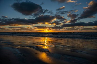 Ocean sunset landscape with soft evening sea water waves crushing on sandy beach.