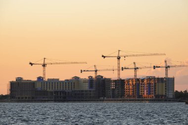 Tower lifting cranes at high residential apartment buildings construction site. Real estate development.