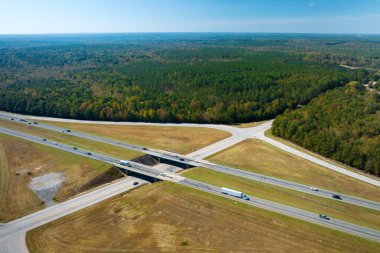 View from above of busy american highway with fast moving traffic between woods. Interstate transportation concept.