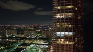 Florida, ABD 'deki Sunny Isles Beach City' de gece vakti aydınlık bir konut binasının yüksek açılı görüntüsü. Modern Amerikan kentsel bölgesinde konut geliştirme.