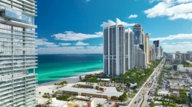 Sunny Isles Beach City 'deki Atlantik Okyanusu kıyısındaki lüks otellerin ve apartmanların manzarası. Kalabalık trafiği olan bir şehir caddesi. Güney Florida 'daki Amerikan turizm altyapısı.