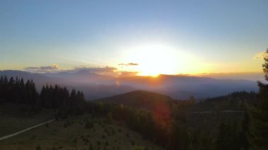 View from above of ukrainian Carpathian mountains with wooded hills at autumnal sunset. Brightly illuminated with setting sun pine woods in fall season.