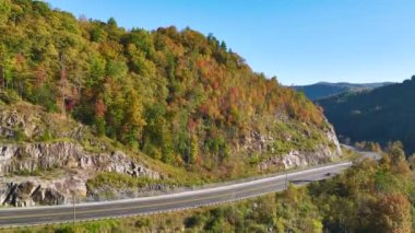 High point of view of highway route in North Carolina through Appalachian mountains in golden fall season with fast moving trucks and cars. Interstate transportation concept.
