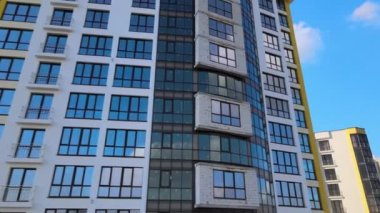 High residential apartment building with monolithic frame and glass windows under construction. Real estate development.