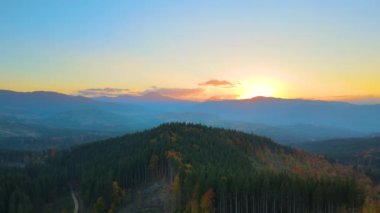 Güzel bir akşam panoramik manzarası. Gün batımında uzak dağ tepeleri üzerinde parlak batan güneş..