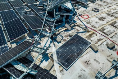 Yeşil ekolojik elektrik üretmek için endüstriyel yapı çatısına monte edilen rüzgar fotovoltaik güneş panellerinden hasar gören hava görüntüsü. Doğal afetin sonuçları..