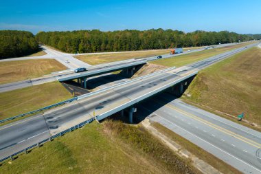 Aerial view of freeway overpass junction with fast moving traffic cars and trucks in american rural area. Interstate transportation infrastructure in USA.