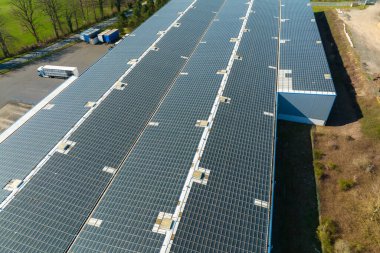 Sanayi binasının çatısına yeşil ekolojik elektrik üretmek için monte edilmiş mavi fotovoltaik panelli güneş enerjisi santralinin hava görüntüsü. Sürdürülebilir enerji konsepti üretimi.