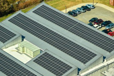 Sanayi binasının çatısına yeşil ekolojik elektrik üretmek için monte edilmiş mavi fotovoltaik panelli güneş enerjisi santralinin hava görüntüsü. Sürdürülebilir enerji konsepti üretimi.