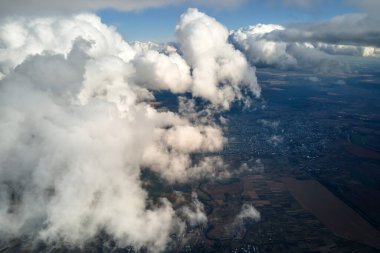 Dünya 'nın yüksek irtifasındaki uçak penceresinden hava manzarası beyaz kabarık kümülüs bulutlarıyla kaplı..