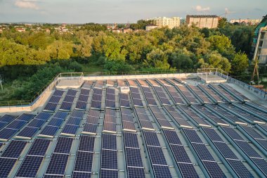 Sanayi binasının çatısına yeşil ekolojik elektrik üretmek için monte edilen mavi fotovoltaik güneş panellerinin hava görüntüsü. Sürdürülebilir enerji konsepti üretimi.