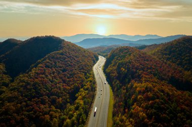 View from above of I-40 freeway route in North Carolina leading to Asheville thru Appalachian mountains with yellow fall woods and fast moving trucks and cars. Interstate transportation concept.