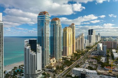 Sunny Isles Beach City 'deki Atlantik Okyanusu kıyısındaki lüks otellerin ve apartmanların manzarası. Kalabalık trafiği olan bir şehir caddesi. Güney Florida 'daki Amerikan turizm altyapısı.