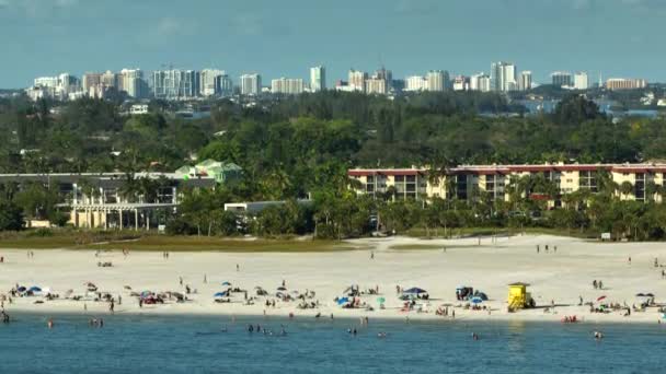 アメリカのサラソータで観光客でいっぱいの白い砂浜とシエスタキービーチの上からの眺め 多くの人々はメキシコ湾の水で泳いだり 暖かいフロリダの太陽の下でリラックスして休暇を楽しんでいます — ストック動画