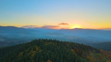 Gün batımında puslu tepeleri ve sisli vadisi olan güzel panoramik dağ manzarası.