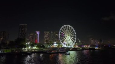 Bayside Pazarı 'ndaki Miami Gözlem Çarkı' nda Biscayne Körfezi suyuna yansıyan yansımalar ve Brickell 'in yüksek aydınlatmalı gökdelenleri, finans merkezi. ABD şehir manzarası geceleyin.