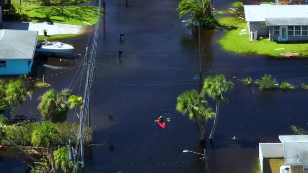 ハリケーンイアンに囲まれた浸水した通りに浮かぶカヤックボートフロリダ州の住宅地の洪水の水の家 自然災害の結果 — ストック動画