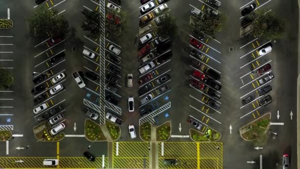 食料品店の前の明るく照らされた駐車場で夜に駐車された多くの車のトップビュー 消費主義と市場経済の概念 — ストック動画
