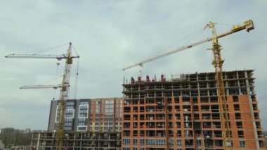 Tower lifting cranes at high residential apartment buildings construction site. Real estate development.