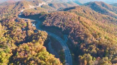 Aerial view of highway road in North Carolina through Appalachian mountains in golden fall season with fast moving trucks and cars. Interstate transportation concept.