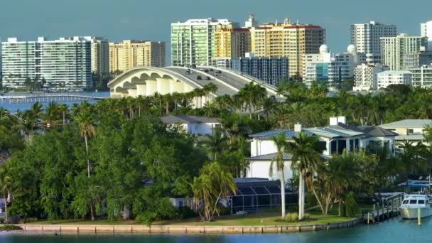 美国佛罗里达州萨拉索塔市绿色棕榈树之间昂贵的滨水房屋 市区高层办公大楼在地平线上 高级住房开发 — 图库视频影像