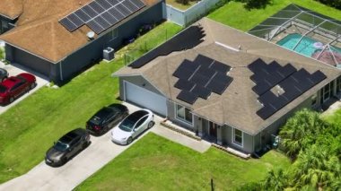 Standard american residential house with rooftop covered with solar photovoltaic panels for producing of clean electrical energy in suburban rural area. Concept of investment in autonomous home.