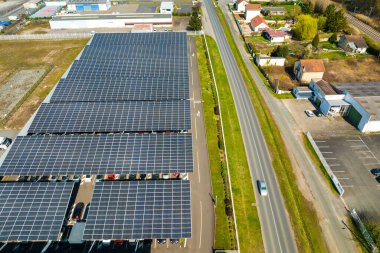 Güneş panellerinin hava görüntüsü park yerinin üzerine gölge çatısı olarak yerleştirilmiş ve temiz elektriğin etkin üretimi için park edilmiş arabalar var. Fotovoltaik teknoloji şehir altyapısına entegre edildi.