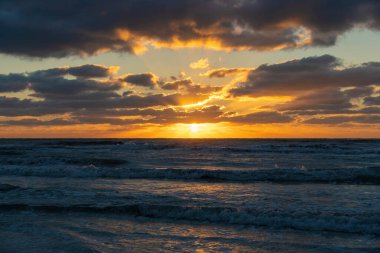 Ocean sunset landscape with soft evening sea water waves crushing on sandy beach.