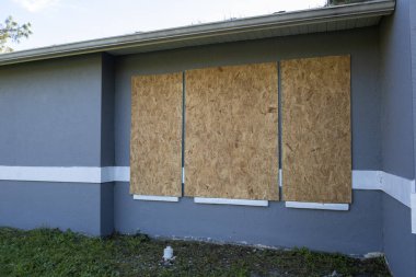 Plywood storm shutters for hurricane protection of house windows. Protective measures before natural disaster in Florida. clipart