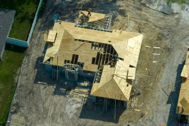 Florida kırsal kesiminde ahşap iskeleti olan bitmemiş bir banliyö evinin çatı inşaatında çalışan profesyonel müteahhitler. Amerika 'da konut geliştirme kavramı.