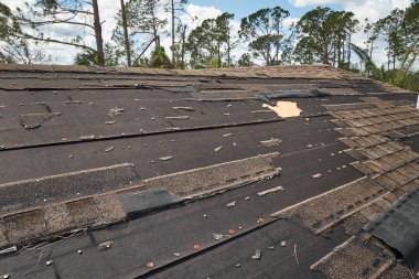 Wind damaged house roof with missing asphalt shingles after hurricane Ian in Florida. Repair of home rooftop concept. clipart