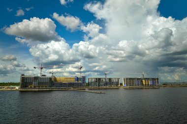 Deniz kıyısındaki inşaat alanındaki yüksek konut binalarının vinçleri ve iskelet yapısı. Gayrimenkul geliştirme.