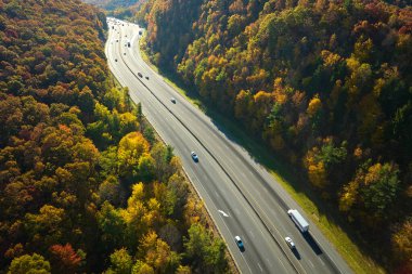 View from above of I-40 freeway route in North Carolina leading to Asheville thru Appalachian mountains with yellow fall woods and fast moving trucks and cars. Interstate transportation concept.
