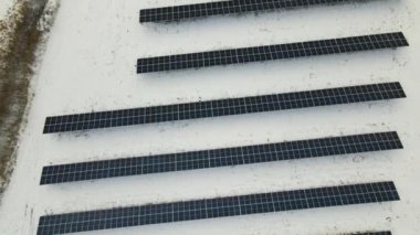 Aerial view of snow melting from covered solar photovoltaic panels at sustainable electric power plant for producing clean electrical energy. Low effectivity of renewable electricity in winter.