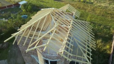 Aerial view of unfinished residential house with wooden roof frame structure under construction.