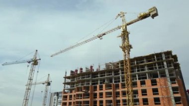 Tower cranes and frame structure of high residential apartment buildings at construction site. Real estate development.