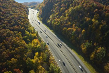 I-40 freeway road leading to Asheville in North Carolina thru Appalachian mountains with yellow fall forest and fast moving trucks and cars. Concept of high speed interstate transportation.