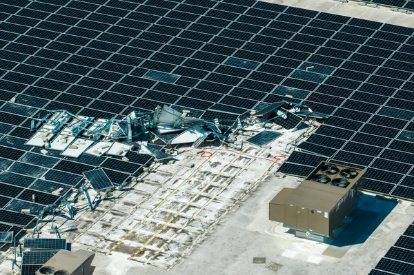 stock image Aerial view of damaged by hurricane wind photovoltaic solar panels mounted on industrial building roof for producing green ecological electricity. Consequences of natural disaster.