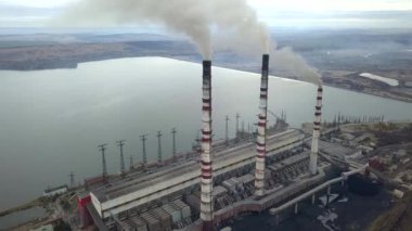 Kömür santralinden gelen gri dumanlı yüksek baca borularının havadan görüntüsü. Fosil yakıtla elektrik üretimi.