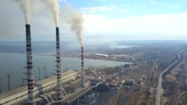 Kömür santralinden gelen gri dumanlı yüksek baca borularının havadan görüntüsü. Fosil yakıtla elektrik üretimi.