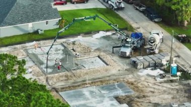 Yeni ev inşaatındaki işçilerin havadan görünüşü duvarlar ve çatı için beton döşeme temelleri döşemeye hazır..