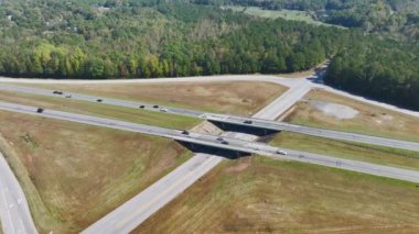 Aerial view of freeway overpass junction with fast moving traffic cars and trucks in american rural area. Interstate transportation infrastructure in USA.