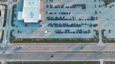 Geniş Amerikan otoyolunun yakınında satılık bir sürü yeni arabasıyla bayilik otoparkının havadan görüntüsü. ABD otomotiv sanayii kavramının geliştirilmesi.