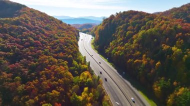 I-40 freeway road leading to Asheville in North Carolina thru Appalachian mountains with yellow fall forest and fast moving trucks and cars. Concept of high speed interstate transportation.