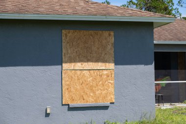Konut evinin kasırga koruması için camları kontraplak fırtına panjurlarıyla kapatılmış. Florida 'daki doğal felaketten önce koruyucu tedbirler.